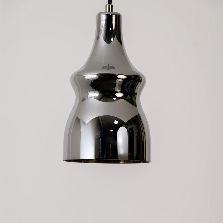 Closeup of the pendant light highlighting its shiny chrome surface smooth contours and modern reflective detailing on a clean backdrop.