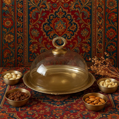 Elegant brass serving cloche displayed on a richly patterned backdrop with dry fruits arranged around it creating a warm festive lifestyle setting.