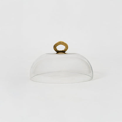Clear glass dome with decorative golden handle in focus showcasing smooth round shape and elegant simplicity.