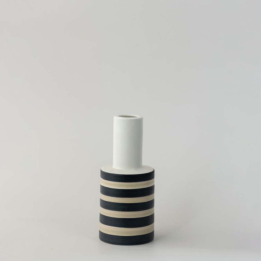Modern striped ceramic vase with black and beige detailing photographed on a clean white background.