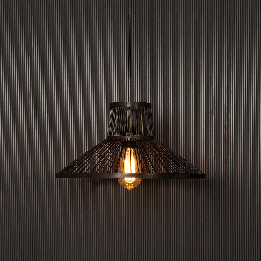 Cone black wire pendant light glowing softly on black background reflecting industrial charm and warm ambience.