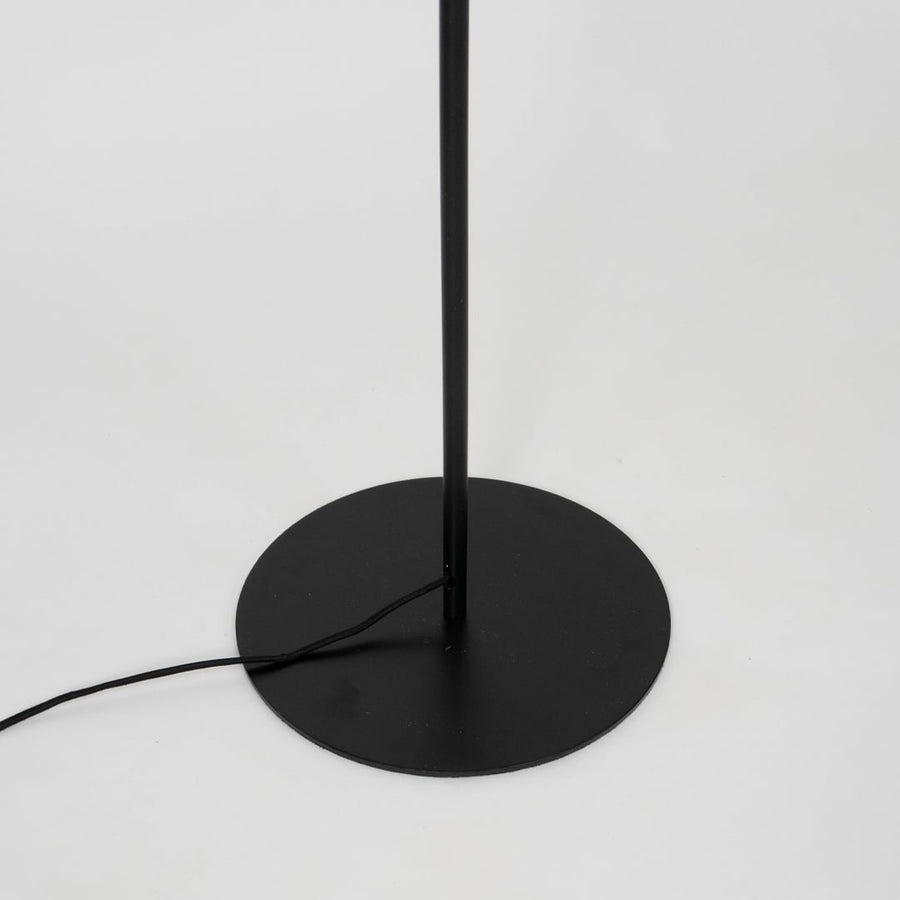 Modern floor lamp with black metal base and angled gold arm supporting matte black shade for reading or decor lighting.