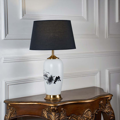 White ceramic table lamp with black abstract pattern gold base and black shade shown unlit on a white background highlighting its bold modern design.
