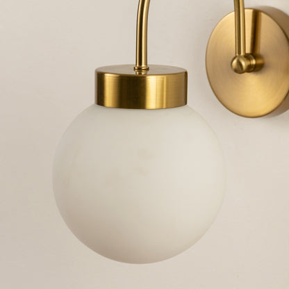 Wall light with gold mount and white glass globe on neutral background modern decorative lighting ideal for bedroom decor.
