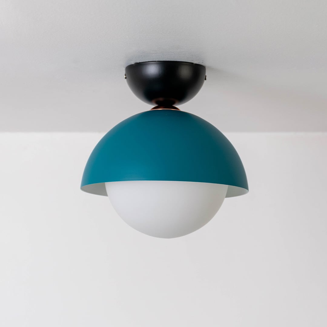 Ceiling light shown off on a white background featuring a teal dome shade matched with a white globe.
