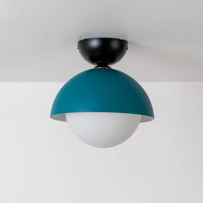 Ceiling light shown off on a white background featuring a teal dome shade matched with a white globe.