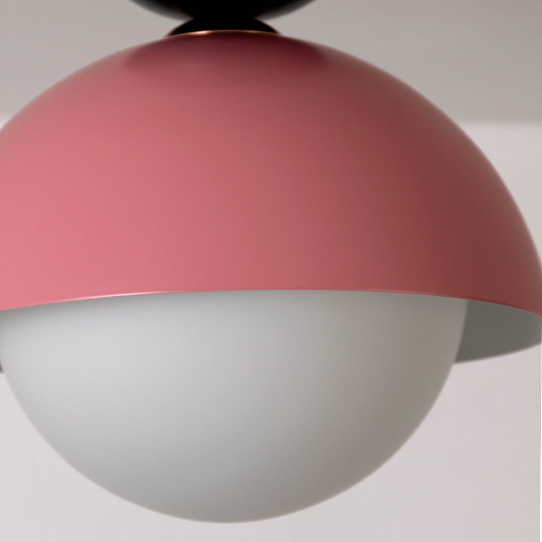 Closeup view of the pink dome ceiling light highlighting its smooth finish and simple round white globe design.