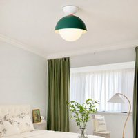 Modern ceiling light in a soft room setting with a green dome shade and a round white globe for gentle ambient lighting.