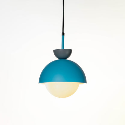 Minimal teal metal pendant ceiling light with soft glowing glass globe shade suspended on cord against neutral white wall background for modern homes.
