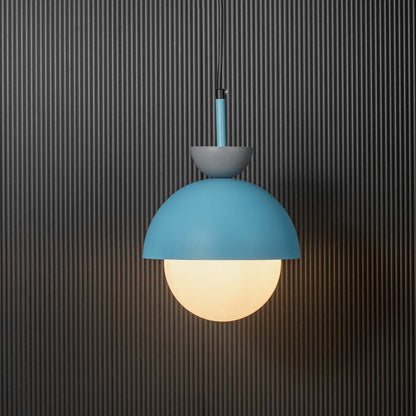 Contemporary pendant light in matte blue metal with frosted glass globe shade glowing beautifully against dark backdrop.