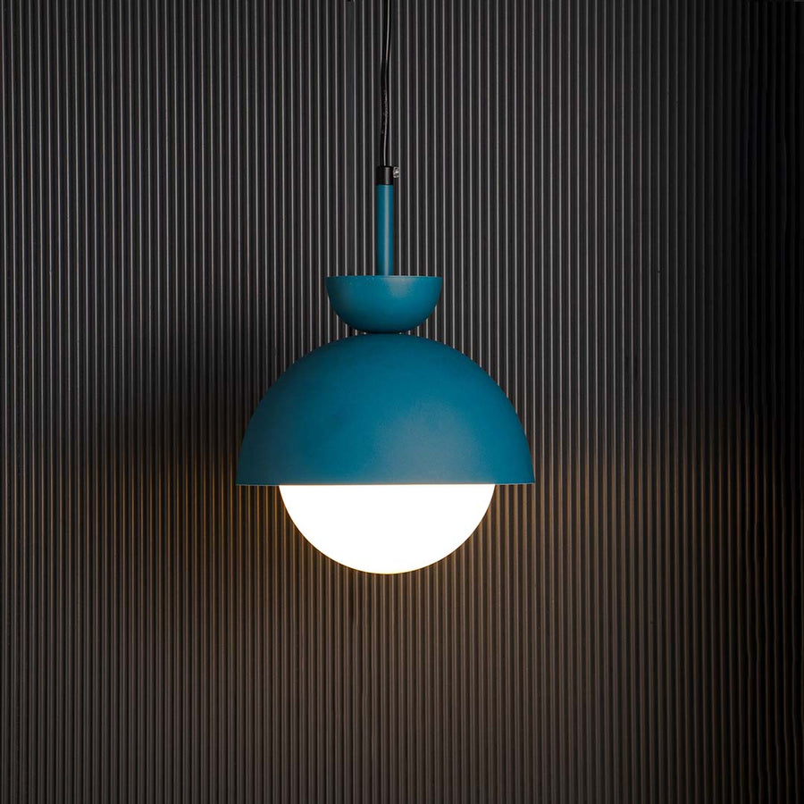 Blue dome pendant ceiling light with frosted white globe glowing warmly against black background creating stylish home interior.