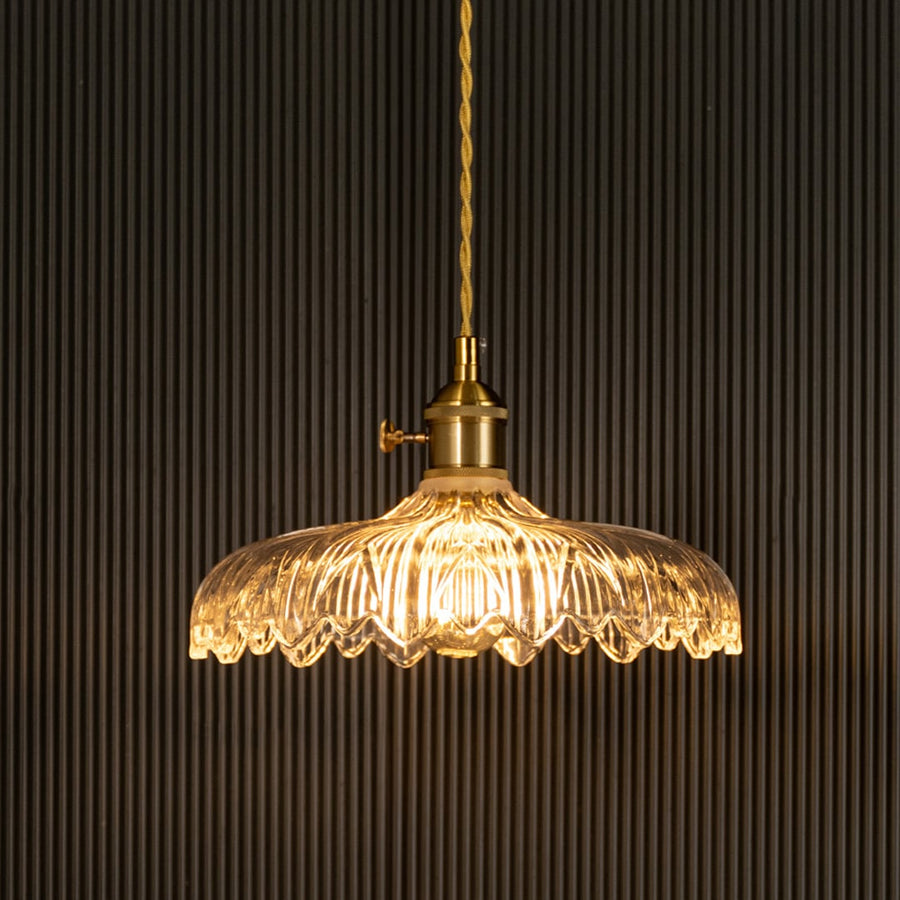 Crystal glass pendant light with brass frame illuminated for sophisticated ceiling decor.
