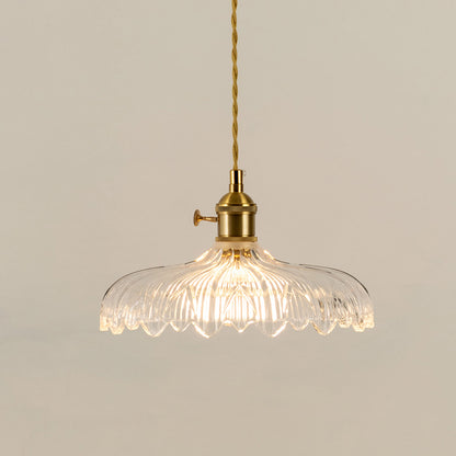 Illuminated clear patterned glass pendant light with gold fittings creating soft ambient lighting indoors.