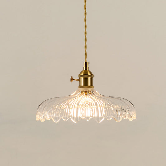 Illuminated clear patterned glass pendant light with gold fittings creating soft ambient lighting indoors.