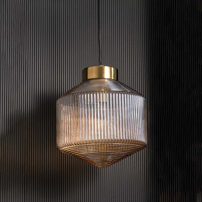Amber ribbed glass pendant light shown with light off on a dark background highlighting its sculpted lines reflective surface and gold cap.