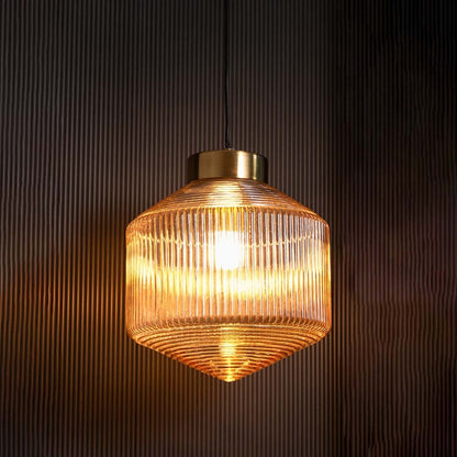 Ribbed amber glass pendant light displayed with light on against a dark backdrop enhancing its glowing warm tones and elegant ribbed glass design.