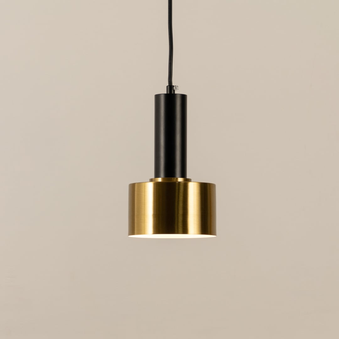 Gold and black metal pendant light with bulb switched on shown against a clean white background highlighting its modern minimal design.