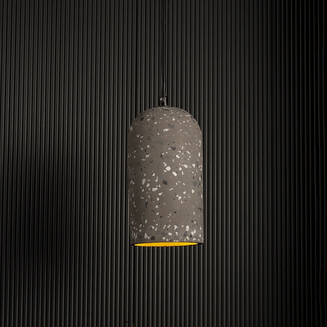 Warm glowing terrazzo pendant light highlighting its grey textured surface against a dark background for a modern industrial look.
