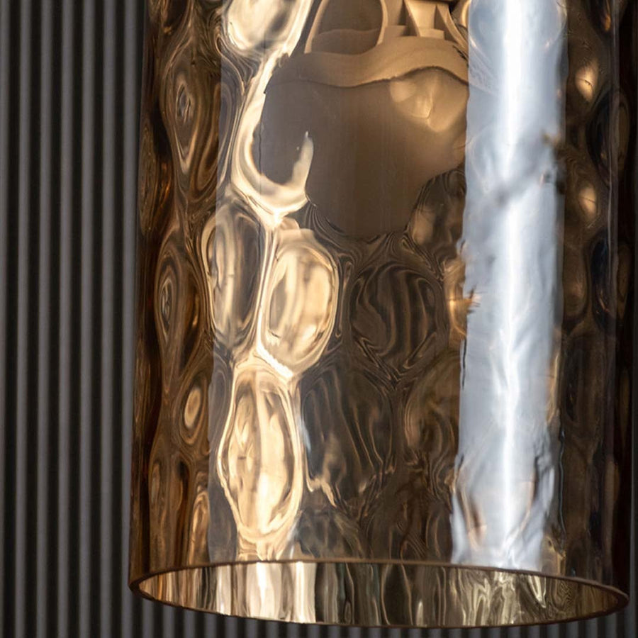 Closeup of hammered gold metal pendant shade highlighting reflective texture handcrafted finish and premium decorative lighting detail.