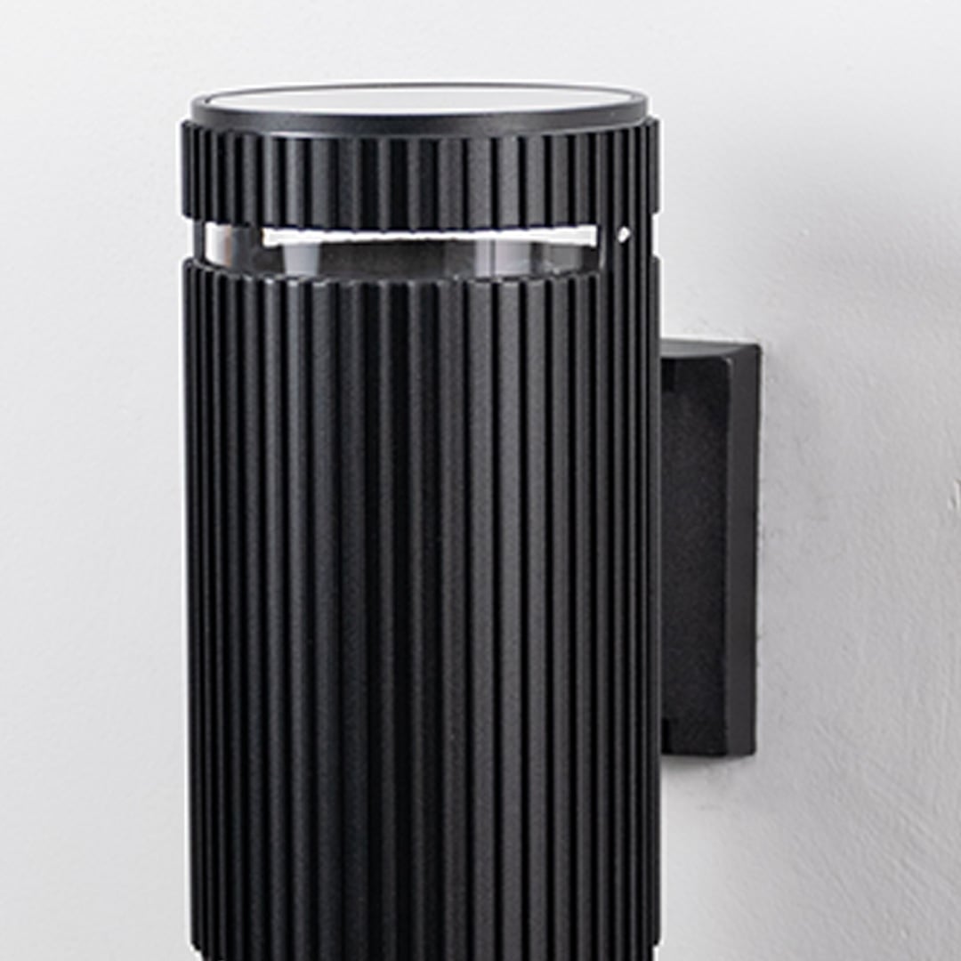 Closeup of black ribbed wall light showcasing detailed vertical grooves and refined matte finish.