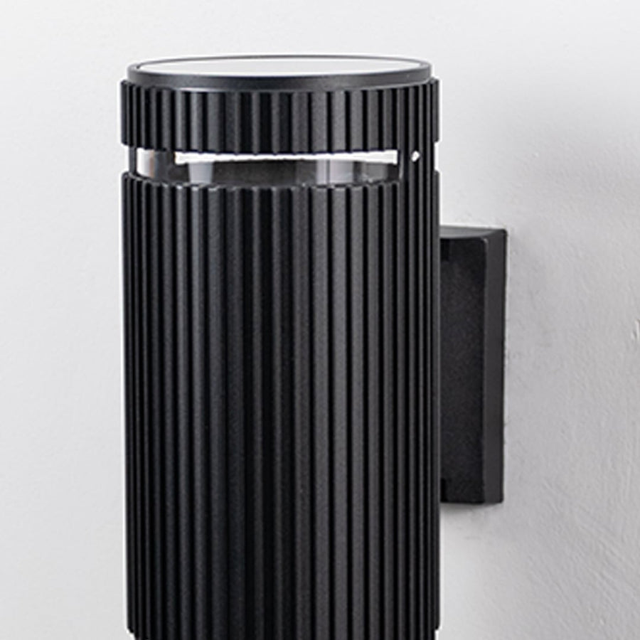 Closeup of black ribbed wall light showcasing detailed vertical grooves and refined matte finish.