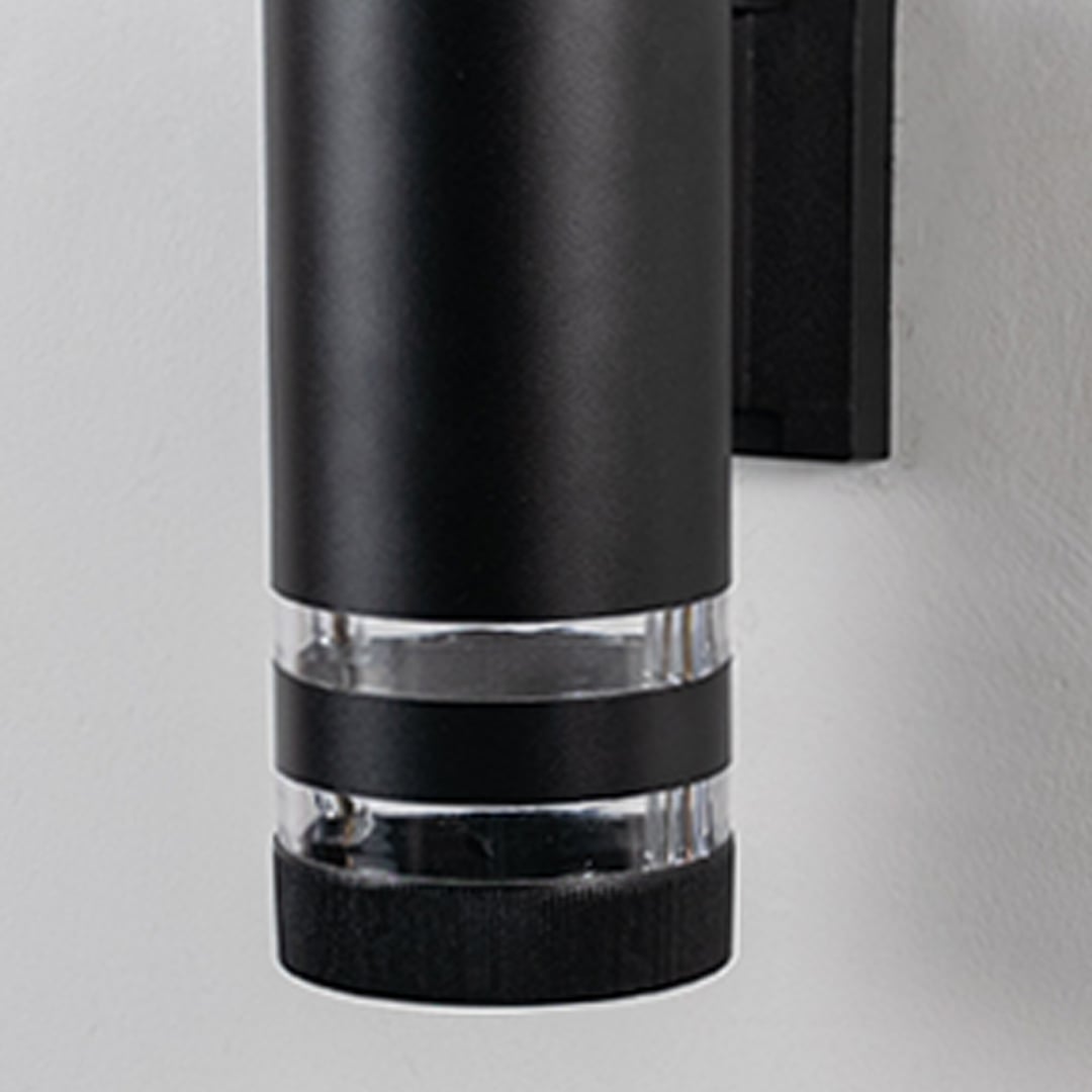 Closeup view of black cylindrical wall light showcasing its matte finish and polished acrylic detailing.
