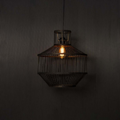 Black wire pendant light glowing warmly against black background highlighting industrial craftsmanship and soft radiance.