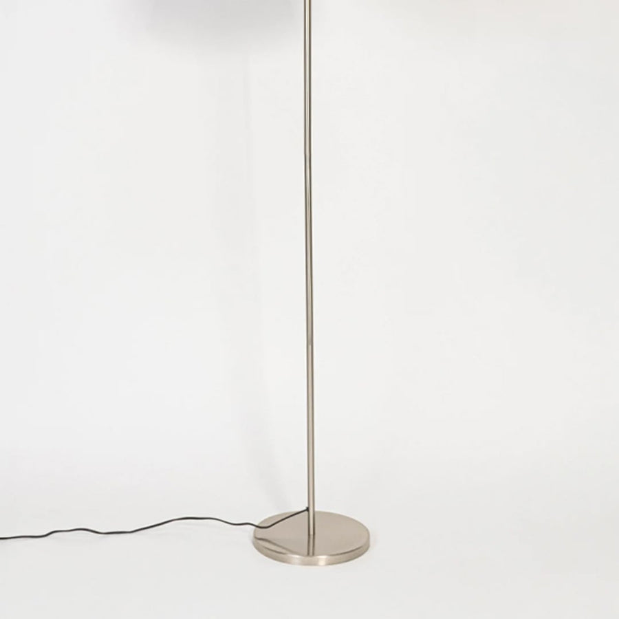 Minimal floor lamp with brushed silver metal stem and circular base shown on white background for clean modern interior styling.