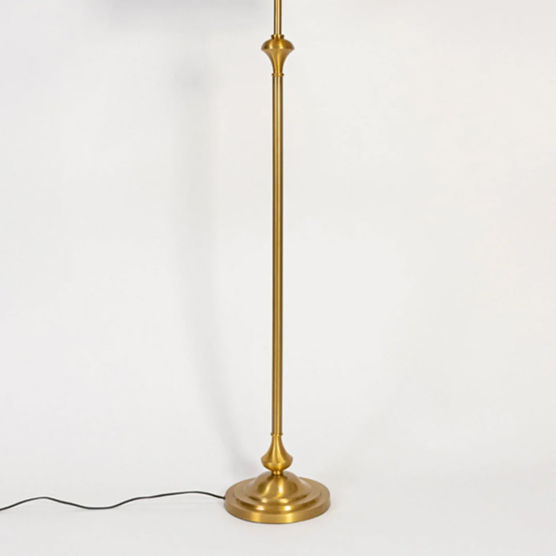 Modern floor lamp with slim gold metal stem and round base placed on white background for elegant living room lighting.