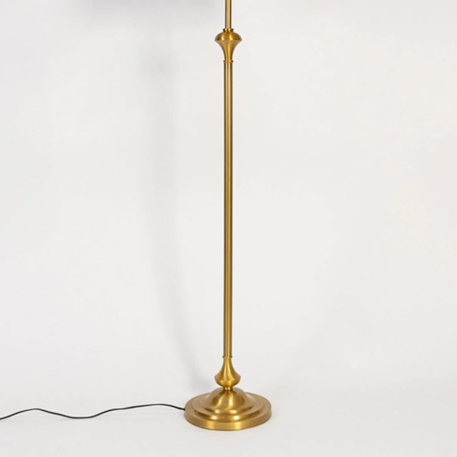 Modern floor lamp with slim gold metal stem and round base placed on white background for elegant living room lighting.