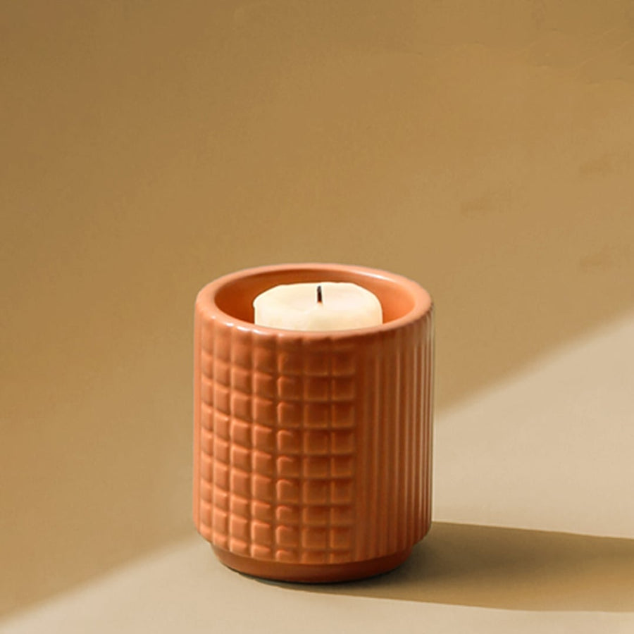 Modern terracotta ceramic candle holder with embossed texture shown on white background for elegant tabletop styling.