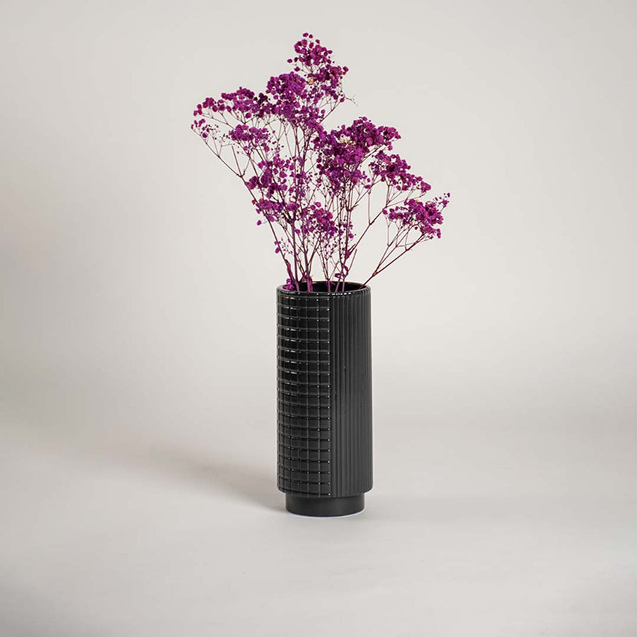 Tall black ceramic textured vase placed in a stylish interior space perfect for hallways living rooms and modern decor accents.