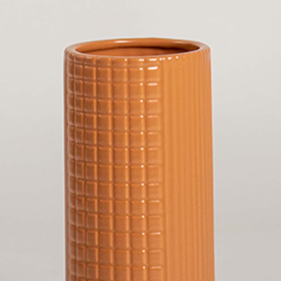 Closeup of terracotta ceramic vase with textured grid pattern showcasing handcrafted details and modern decorative styling.