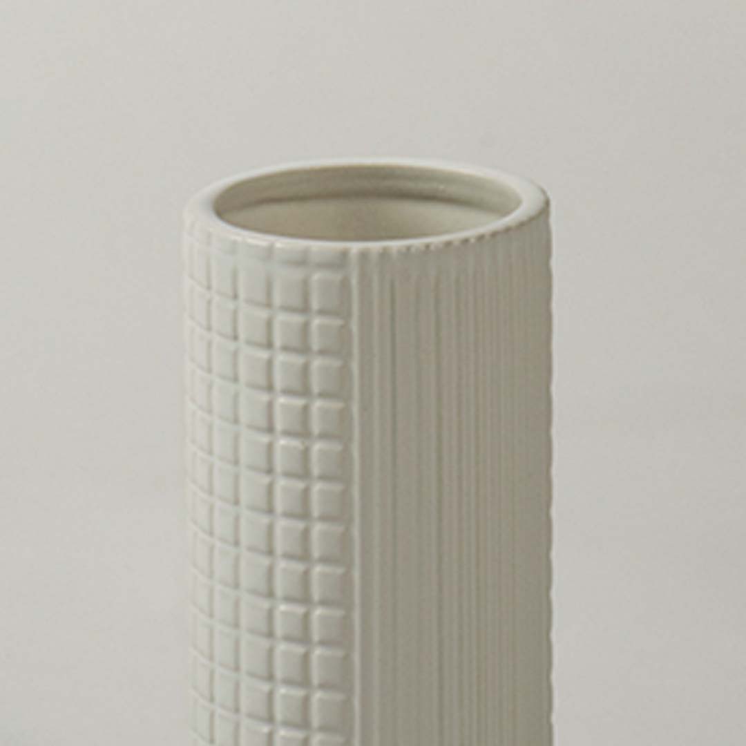 Closeup of ivory ceramic decorative vase with textured grid pattern showcasing refined craftsmanship and modern styling.