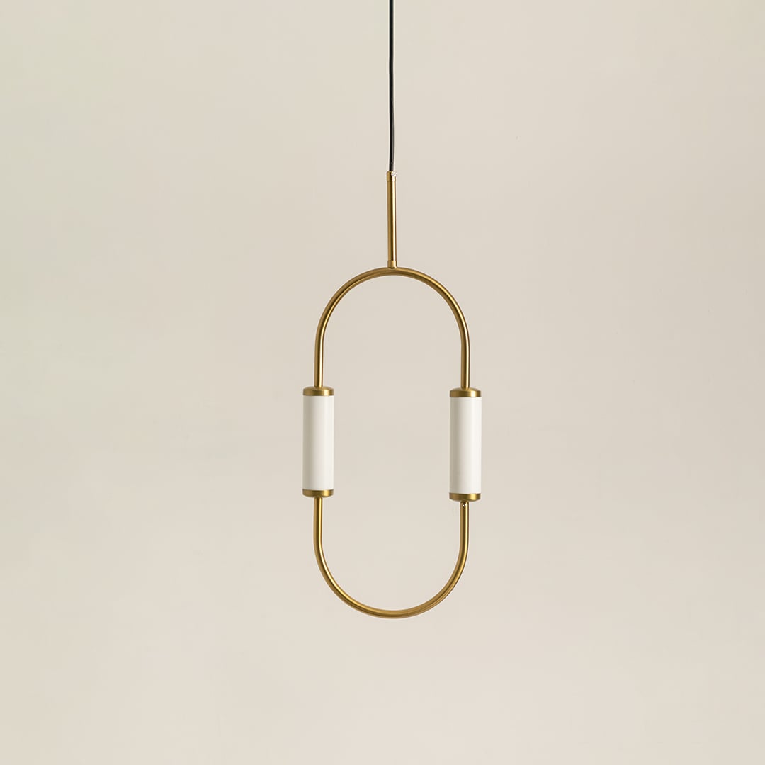 Modern dual light brass pendant chandelier with white cylindrical shades switched off on minimal white backdrop display.