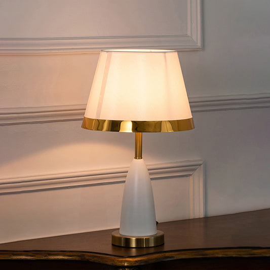 White ceramic table lamp with fabric shade and gold accents offering refined traditional decor and warm ambient lighting.