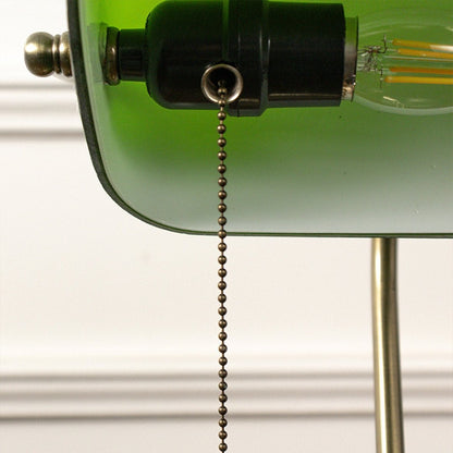 Macro shot of brass base and green glass top of banker table lamp revealing elegant texture and vintage finish.