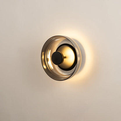 Black wall light with smoked glass shade glowing softly on white background ideal for bedrooms and living spaces.