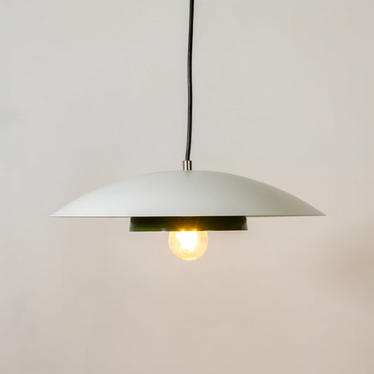 White metal pendant light glowing softly with green inner plate on white background for modern kitchen dining home decor.