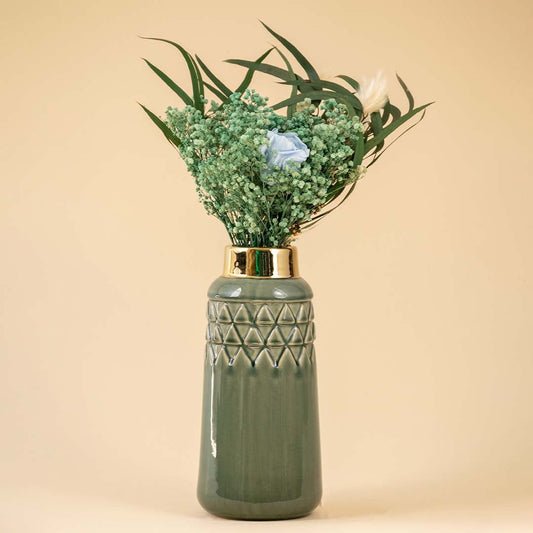 Elegant textured green ceramic vase with golden rim filled with green leaves and delicate florals creating a natural and refreshing display against a beige background.