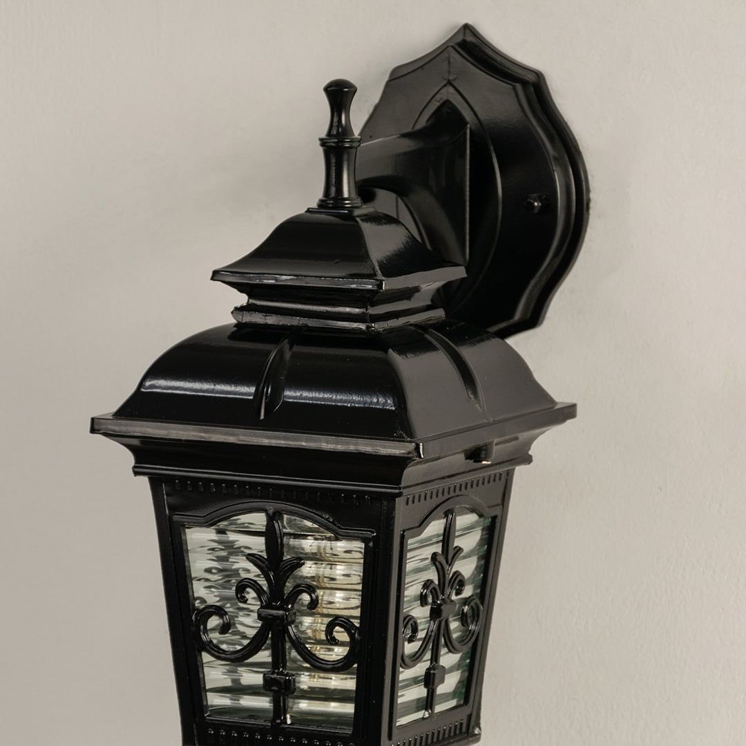 Closeup of black outdoor lantern showing detailed decorative glass panels and classic metal top design suitable for porch patio and entryway decor.