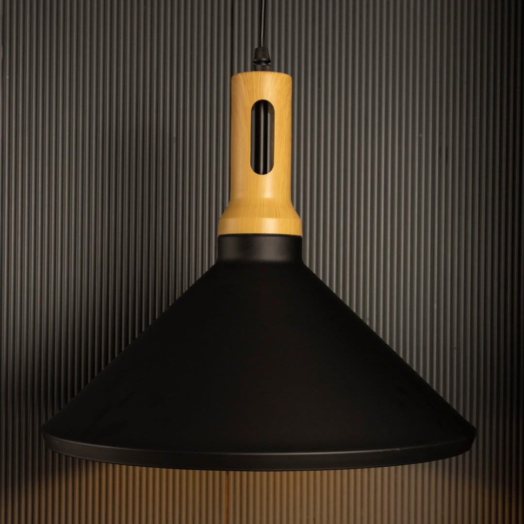 A black wood pendant light switched on against a black background where the warm light shines brightly and the wooden accent contrasts with the dark backdrop.