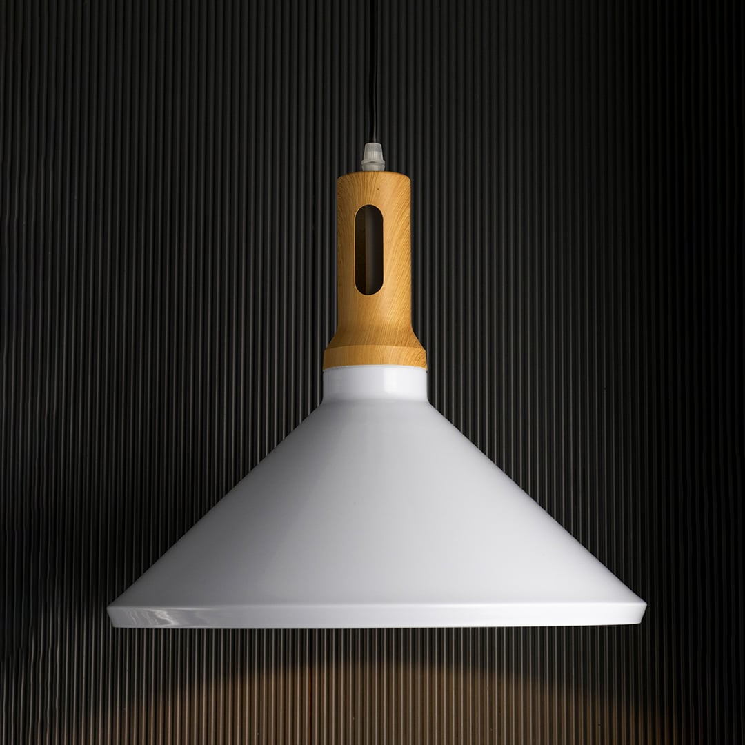 A contemporary pendant lamp with a white shade and warm wooden detail casting a soft glow against a dark black background while the light is on.