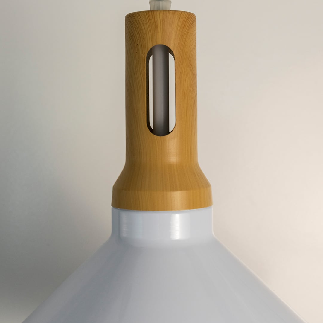 A detailed closeup view of a pendant light showing the wooden top section and smooth white shade highlighting the clean craftsmanship and modern finish.