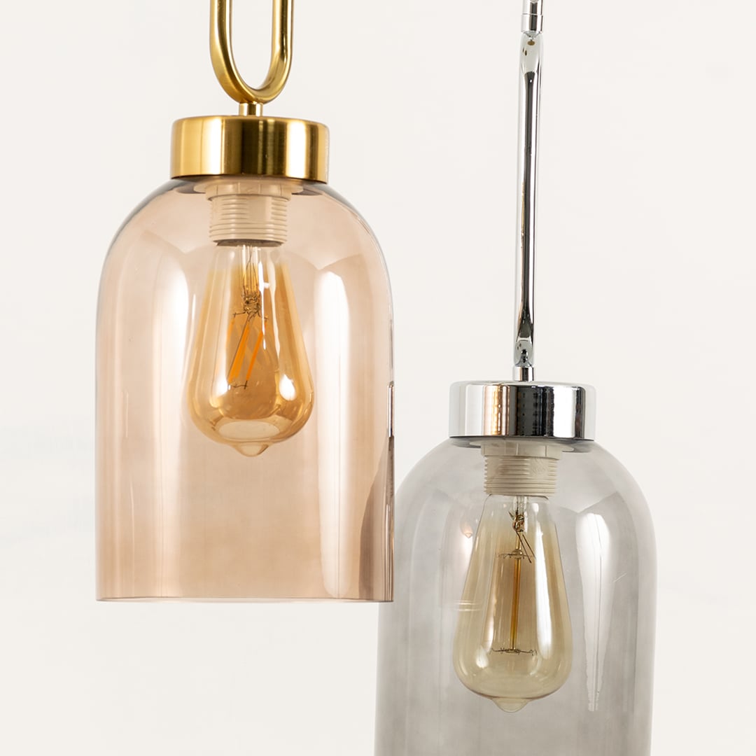 Closeup of dual glass pendant hanging lights featuring amber and smoke grey shades with sleek metal for modern home interiors.