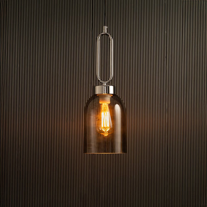 Light on pendant lamp with warm glowing filament inside amber glass shade suspended against textured black wall creating a modern luxury lighting look.