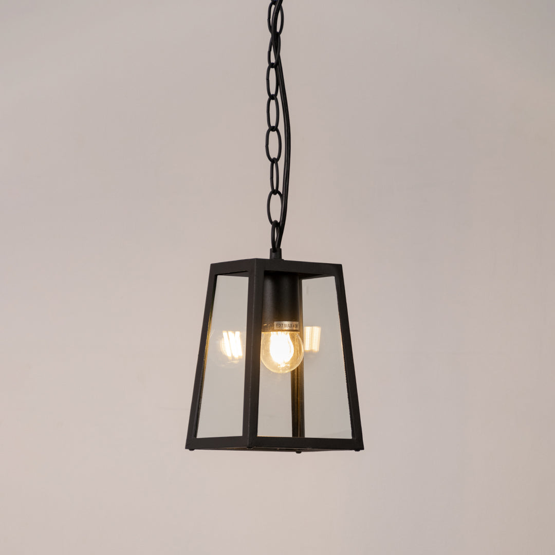 Modern outdoor pendant light in black metal with glass panels for entrance or patio decor lighting white background.