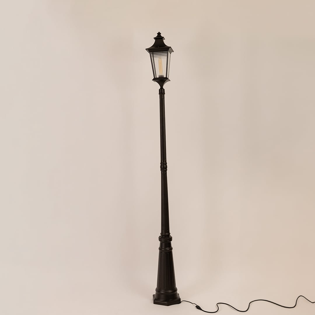 Black metal outdoor lamp post with clear glass lantern displayed on white background with light off for product detailing.