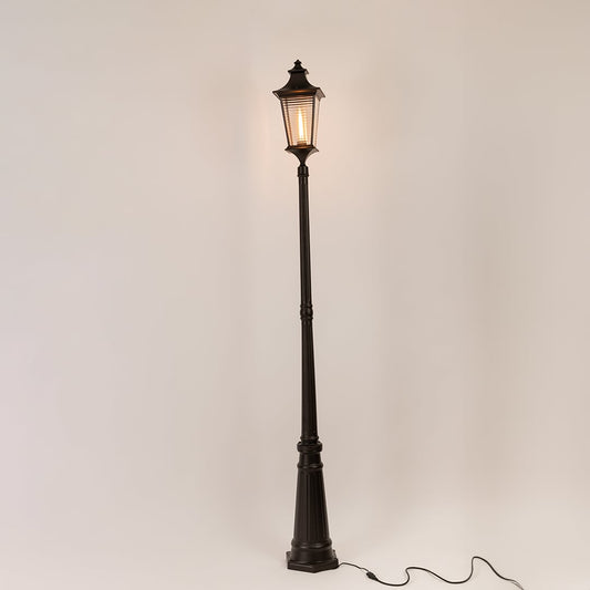 Black metal outdoor lamp post with illuminated clear glass lantern shown on white background for exterior decor display.