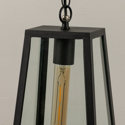 Closeup of black metal hanging outdoor lantern with clear glass panels and bulb on white background perfect for exterior decor lighting.